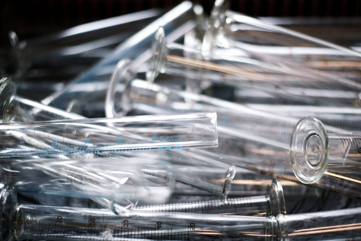 glass test tubes for crafts arranged on wooden table with protective silicone sleeves and calipers measuring wall thickness